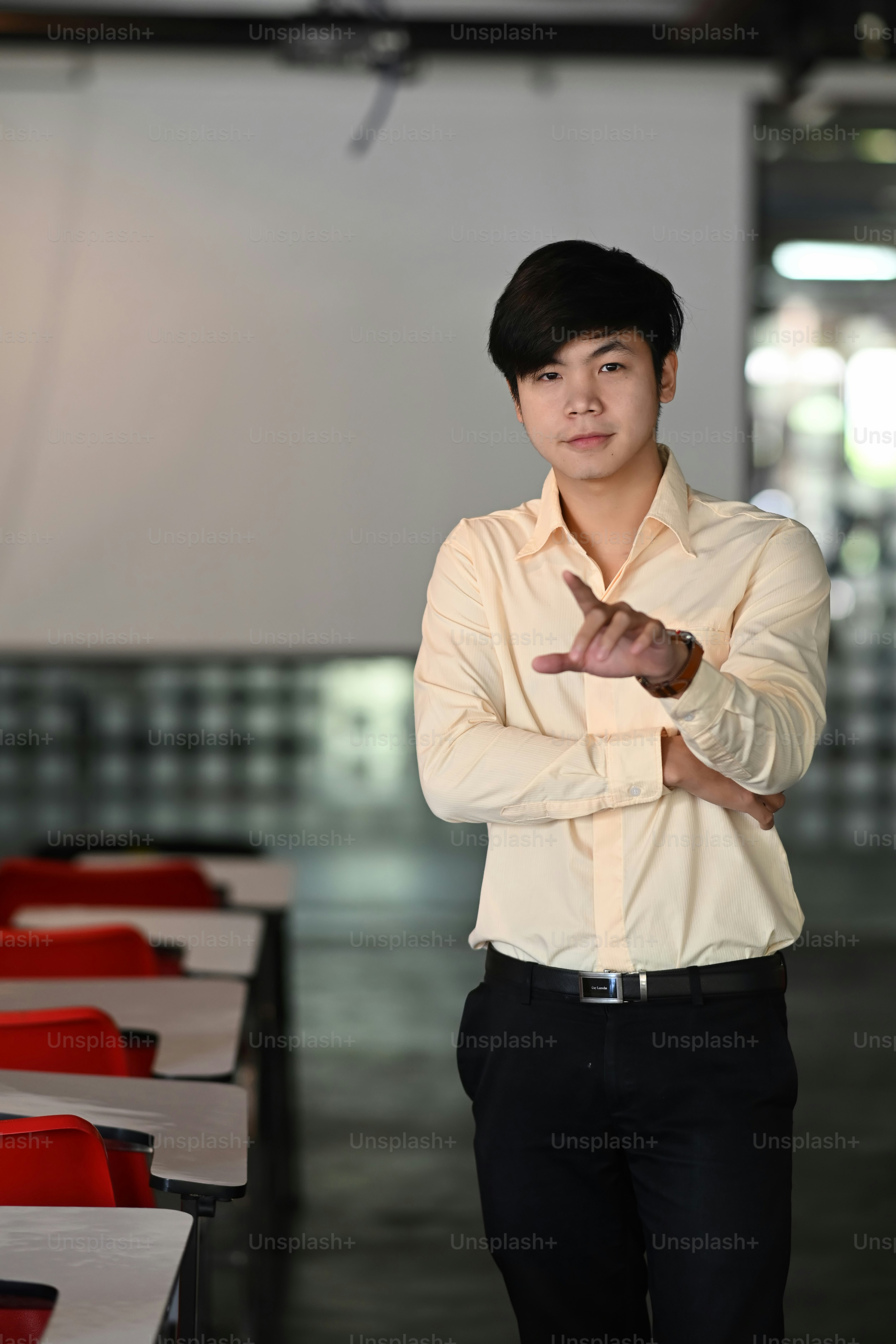 Portrait of a businessman standing in meeting room and pointing finger to camera.